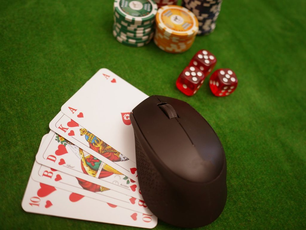 Chips, Würfel und eine Computermaus auf Spielkarten